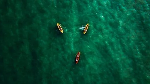 Aerial top-down view on three kayaks with two people in each Stock Photos