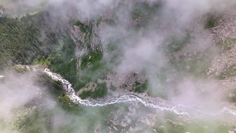 Aerial top-down view through parting clouds of river gorge and forest in Stock Footage 341870696