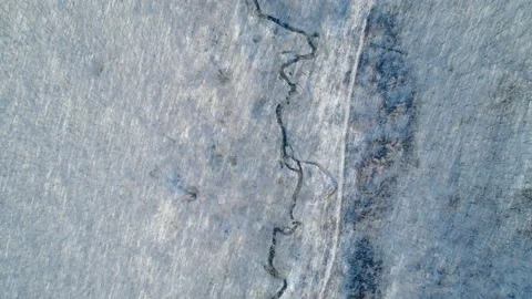 Aerial top down view on a tiny brook between winter ice covered trees. Beautiful Stock-Footage 153686113