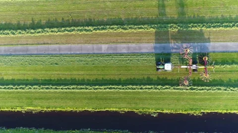 Aerial top-down view of tractor raking grass flying back left 4k Stock Footage 76783139