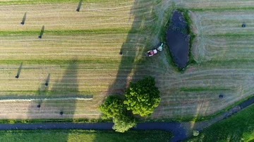 Aerial top down view of tractor pulling platic bale wrapping machinery 4k Stock Footage 85694620