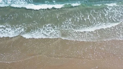 Aerial top down view of turquoise ocean waves breaking on a sandy beach. 스톡 동영상 331402955