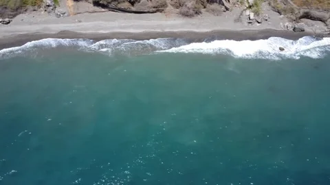 Aerial top down view of turquoise ocean waves crashing on a sandy shoreline Stock Footage 338070240