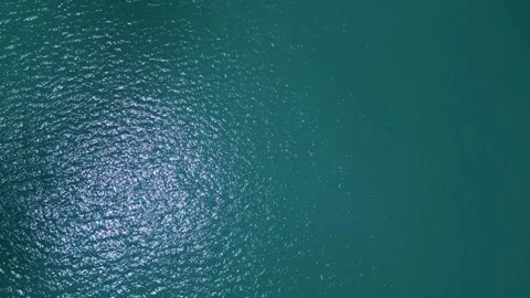 Aerial top down view of turquoise sea water surface with sun glares 動画素材 339322419