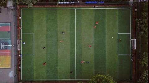 Aerial top down view two boys teams compete play football outside in green .. Vídeos de archivo 279060223