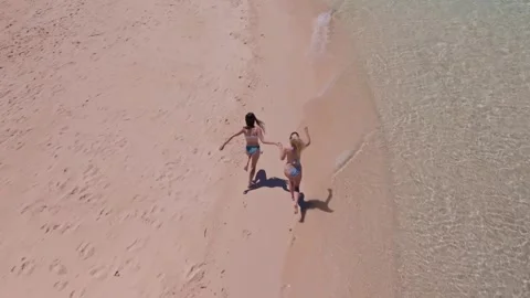 Aerial top down view of two friends girls holding hands on tropical beach island Stock Footage 282586061