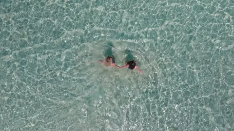 Aerial top down view of two friends girls holding hands on tropical beach island Video stock 282586131