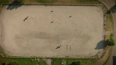 Aerial Top Down View of Two Horses and Riders Circling in Ranch Stable Video stock 326972167