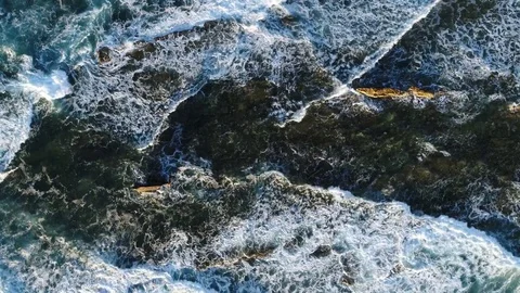 Aerial top down view of waves breaking onto rocks 4k Stock Footage 82727559