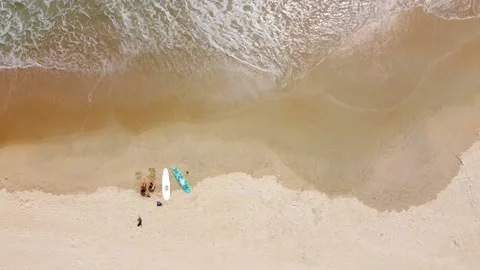 Aerial top down view of waves brushing the sand and surfers with surfboard Stock Footage 154509356