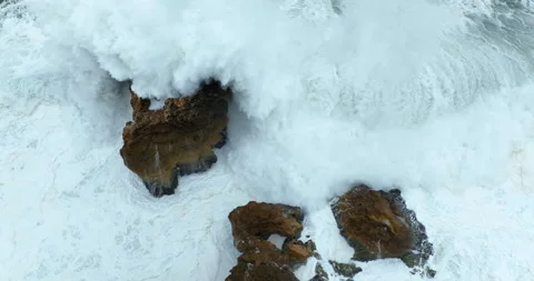 Aerial top down view of waves breaking on rocky cliff. Foamy waves crashing on Stock Footage 221844338