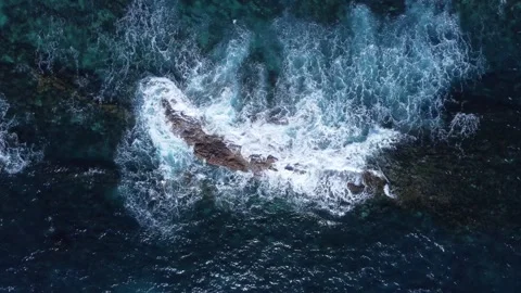 Aerial top-down view of waves crashing against a rocky reef. Video stock 302002046
