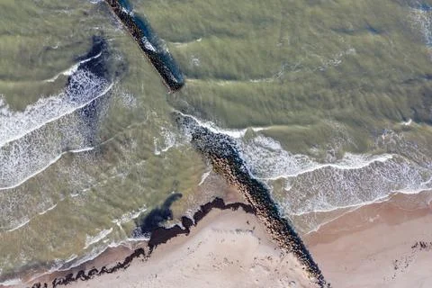 Aerial top down view of waves breaking against old stone breakwater pier Stock Photos