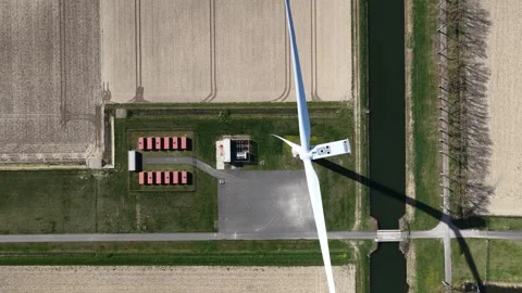 Aerial top down view of wind turbine rotating over farmland Видео 333823219