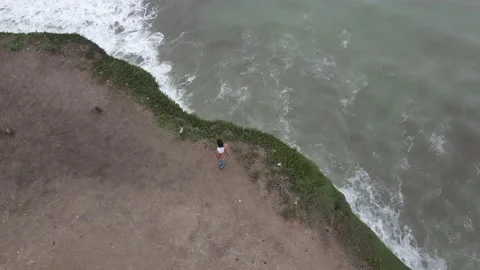 Aerial top down view of young female over cliff front to ocean Stock-Footage 152599731