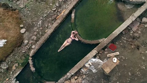 Aerial top down view of a young woman relaxing in natural hot springs cascade Video stock 153413058