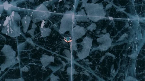 Aerial top down view on the young woman walking on the blue cracked ice of Stock Footage 163158477