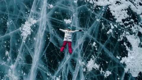 Aerial top down view on the young woman lying on the blue cracked ice of Baikal Stock Footage 163160106