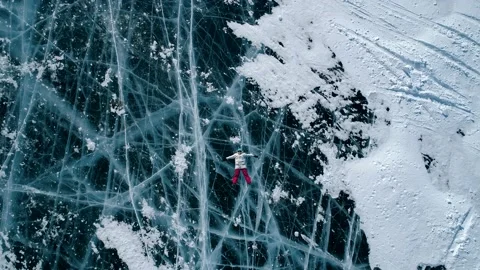 Aerial top down view on the young woman lying on the blue cracked ice of Baikal Stock Footage 163160275