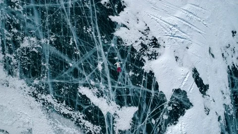 Aerial top down view on the young woman lying on the blue cracked ice of Baikal Stock-Footage 163160484