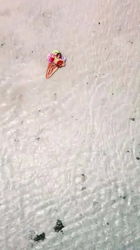 Aerial top-down view of a young woman in a swimsuit relaxing on a colorful 스톡 동영상 344815811