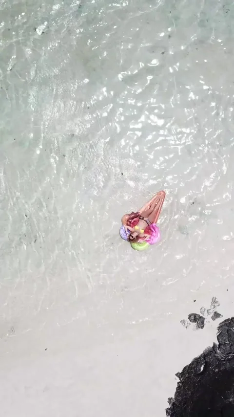 Aerial top-down view of a young woman in a bikini relaxing on a colorful 스톡 동영상 344846251