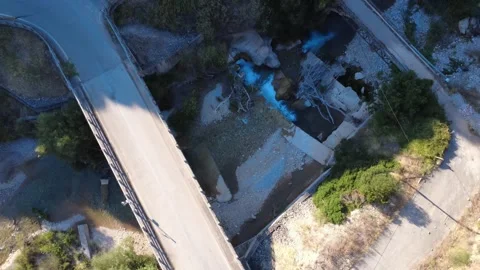 Aerial top down wide angle of a concrete bridge over a rushing mountain river Stock Footage 343961591