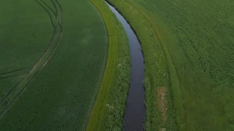 Aerial Top-Down of Winding Stream and Parallel Field Tracks | FlyLens 4K Stockbeeldmateriaal 309049630