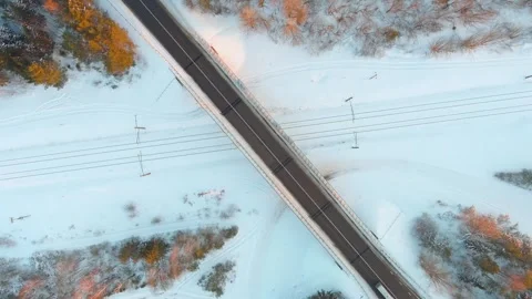Aerial top-down winter sunset view of a road with cars and a railroad crossing 스톡 동영상 312299811