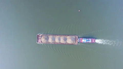 AERIAL: Top view of a barge loaded with sand floats along the river. Stock Footage 87062974