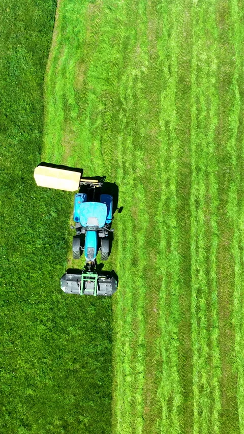 Aerial Top View of Blue Tractor Mowing Green Grass Field Video stock 336567209