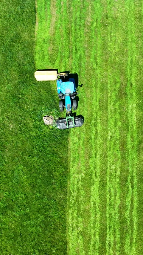 Aerial Top View Of Blue Tractor Mowing Green Grass Field Video stock 336567246