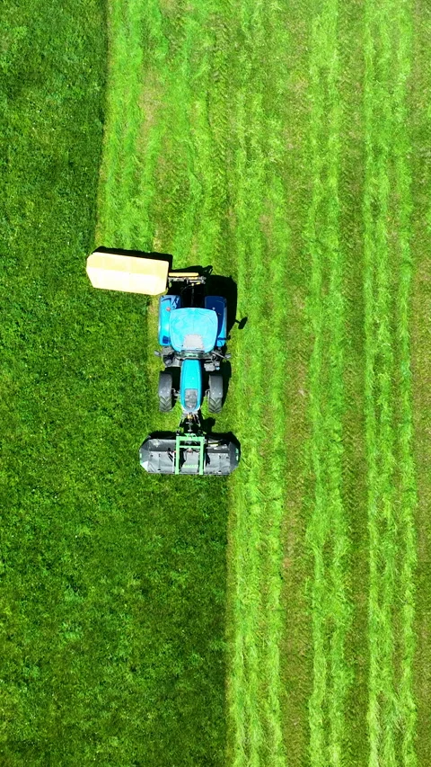 Aerial Top View Of Blue Tractor Mowing Green Grass Field Video stock 336567280