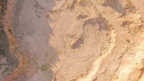 Aerial top view to the bottom of a huge sand pit. A man plays the piano in a Stock Footage 150894730
