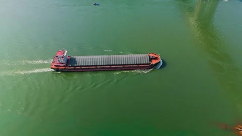 Aerial top view of a cargo ship sailing on a green river. Video stock 330571528
