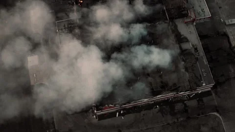 Aerial top view of city block on fire with thick smoke rising, damaged rooftops Stock Footage 303523705