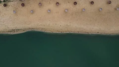 Aerial top view of an empty deserted beach with umbrellas and sun loungers Stock Footage 142889265