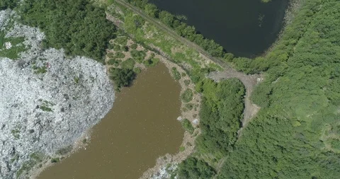 Aerial top view of garbage dump in the middle of the green forest and lake Stock Footage 119247294