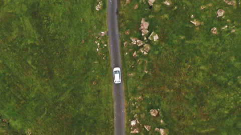Aerial top view of generic electric car driving on country road in Faroe islands Stock Footage