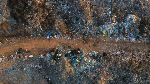 Aerial top view, large garbage pile at sorting site. Camera is truck. Stock Footage 153417347