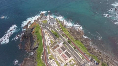 Aerial top view of a lighthouse on cliffs above a turquoise cove 스톡 동영상 343325123