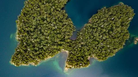 Aerial top view of the lunge-shaped island on dark blue waters lake Stock Photos