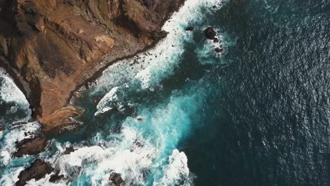 Aerial top view of ocean waves breaking on rocks. Blue water and white foam on Stock Footage 113123589