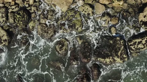 Aerial top view of ocean waves break on rocks or stones. Stock Footage 141761499