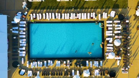 Aerial top view of the open pool with people swimming and sunbathing on sunbeds 動画素材 111789922