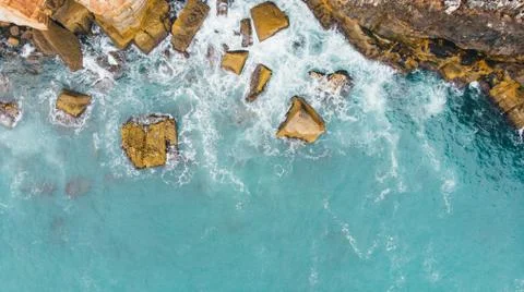 Aerial top view of sea waves hitting rocks on the beach Stock Photos