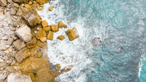 Aerial top view of sea waves hitting rocks on the beach Stock Photos