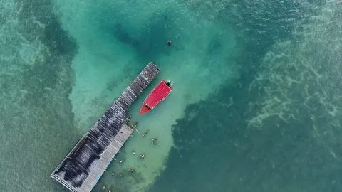Aerial top of view of a small red boat reaching the wooden pier, Martinique Stock Footage 82658661
