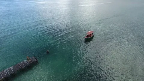 Aerial top of view of a small red boat reaching the wooden pier, Martinique Stock Footage 82658668