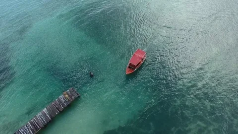 Aerial top of view of a small red boat reaching the wooden pier, Martinique Stock Footage 82658675